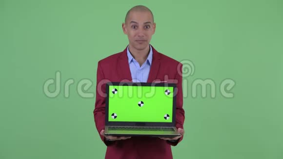 快乐的秃头多民族商人展示笔记本电脑看上去很惊讶视频的预览图