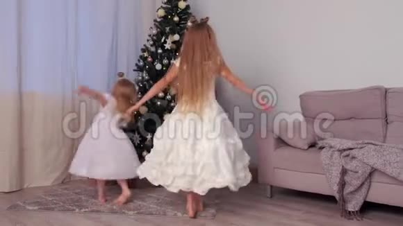 两个姐妹孩子们漂亮的白色连衣裙在圣诞树附近跳舞视频的预览图