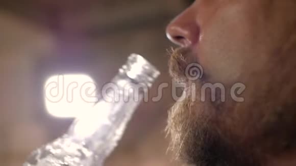 一个长着胡子男人的脸上的特写镜头他从瓶子里喝着啤酒4k视频视频的预览图