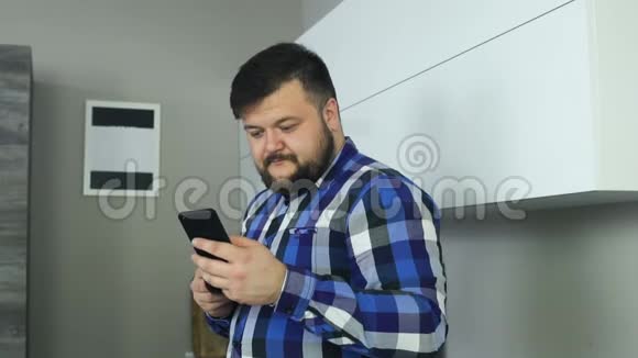 有胡子的人盯着电话翻来覆去胖子刷手机显示器带着一杯咖啡的男人看起来像新闻视频的预览图