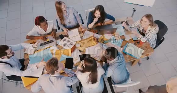 俯视年轻快乐商业创意团队头脑风暴在办公桌经验丰富的女教练给出方向视频的预览图