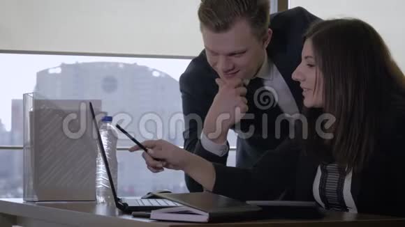 高级经理和女商人用便携式电脑在办公室交谈视频的预览图