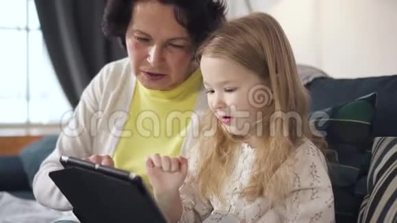 母亲坐在沙发上向女儿展示笔记本电脑的最佳用途视频的预览图