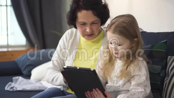 妈妈正在展示迷人的小女孩笔记本电脑和平板电脑的控制屏幕视频的预览图