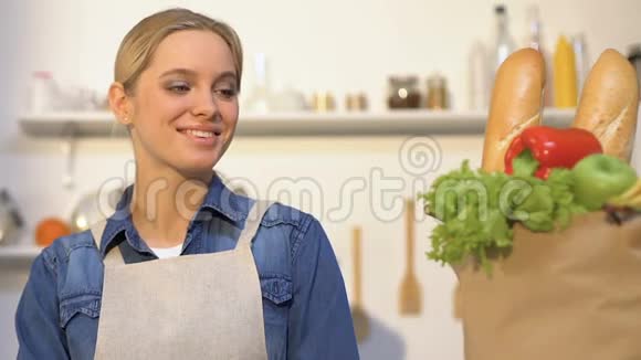 微笑的女人看着装有新鲜面包水果和蔬菜的纸袋视频的预览图