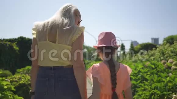 后景金发母亲与女儿在夏园牵手散步家庭幸福单亲家庭连接视频的预览图