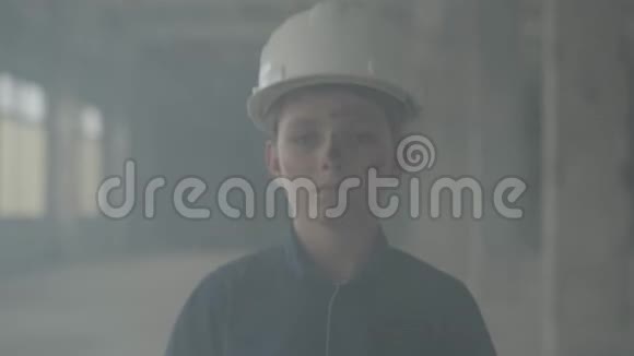 肖像可爱的男孩戴着保护头盔看着镜头背景的室内烟雾火灾概念视频的预览图