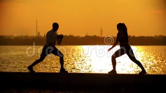 在海滨训练前一对夫妇做热身运动的黑暗轮廓视频的预览图