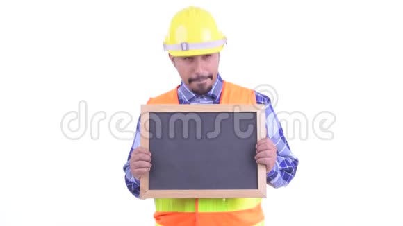 快乐的长胡子的波斯建筑工人一边拿着黑板一边思考视频的预览图