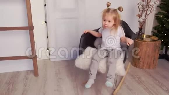 小可爱的女孩在家里的圣诞室内摇椅上摇摆视频的预览图