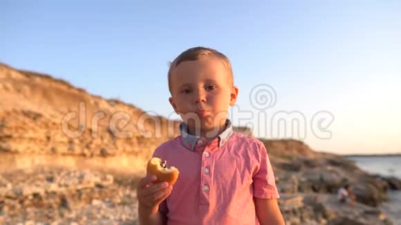 特写小孩吃包子真实的情感海岸背景的男孩视频的预览图