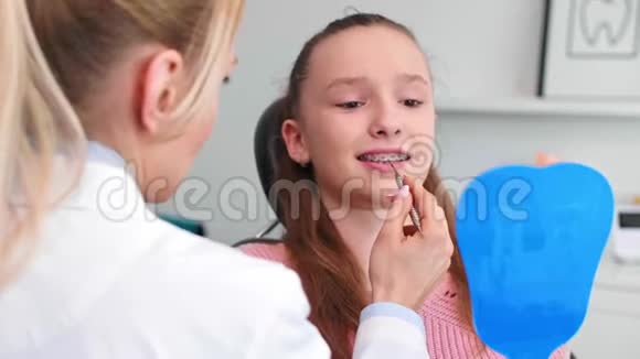 在牙科办公室检查儿童牙齿的女性正畸医生视频的预览图