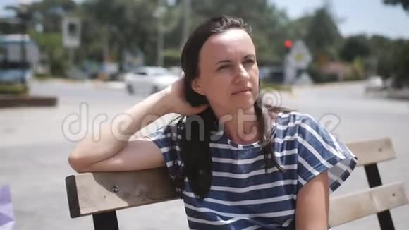 孤独的女人坐在公共汽车站的木凳上休息等待我的公共汽车视频的预览图