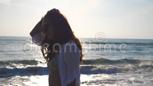穿比基尼和衬衫的漂亮女孩在海滨散步和玩弄她的头发的肖像快乐的年轻女子视频的预览图