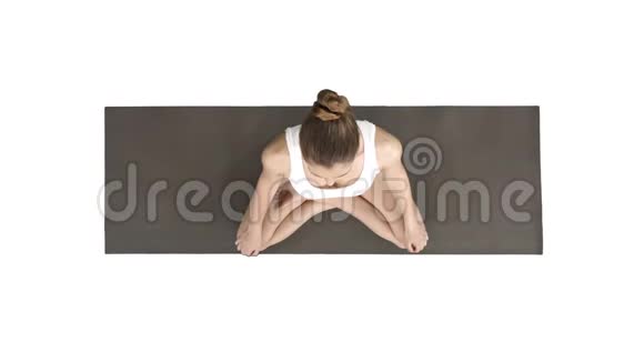 年轻的运动女性练习瑜伽坐在莲花姿势在白色背景上深呼吸视频的预览图