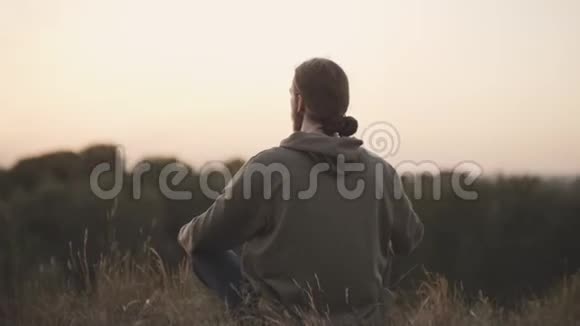 一个长着胡子的白人年轻人坐在莲花的位置上平静地沉思着视频的预览图