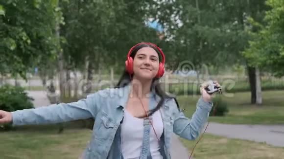 戴着红色耳机的快乐女孩跳起来听音乐视频的预览图