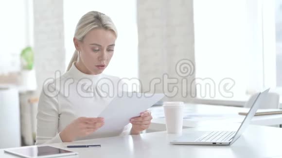 年轻女商人阅读现代办公室文件视频的预览图