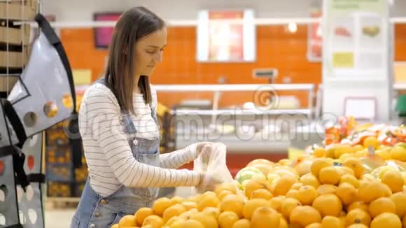 穿牛仔布的年轻女性正在杂货店挑选新鲜橙子视频的预览图