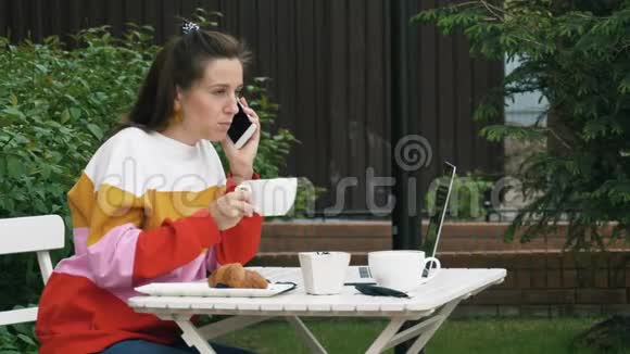 女人喝咖啡用手机说话视频的预览图
