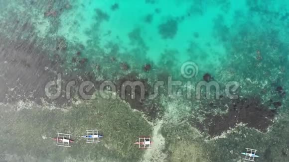 在绿松石透明的海水中有珊瑚礁和深蓝色的中空渔船的空中俯视视频的预览图