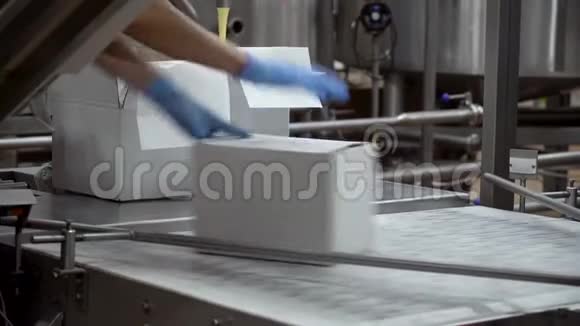 一个工厂工人把一个装满纸板的盒子递给传送带视频的预览图