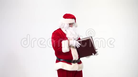 圣诞节白色背景上的圣诞老人在皮封面上读一本大书一页一页的视频的预览图