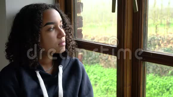 悲伤的美国黑人少女少女坐在窗外视频的预览图