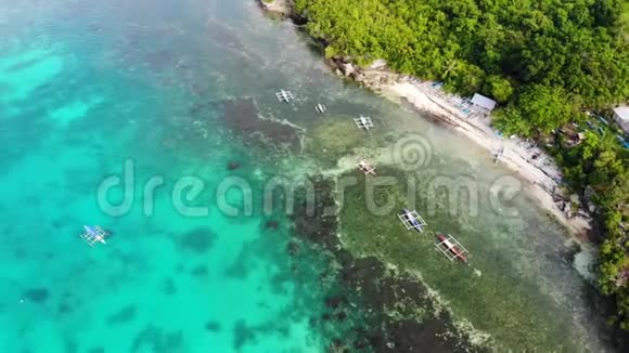 空中无人驾驶飞机拍摄的小沙滩上的小船和珊瑚海岸上的绿松石清水视频的预览图