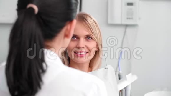 微笑的女人和牙医在牙医诊所谈话视频的预览图