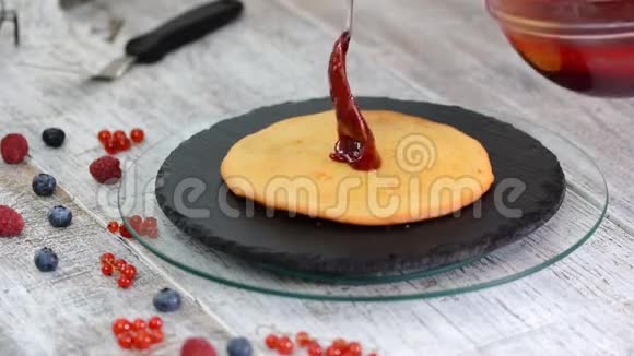 女人把浆果酱放在蛋糕层上在白色背景下在蛋糕上做分层蛋糕视频的预览图