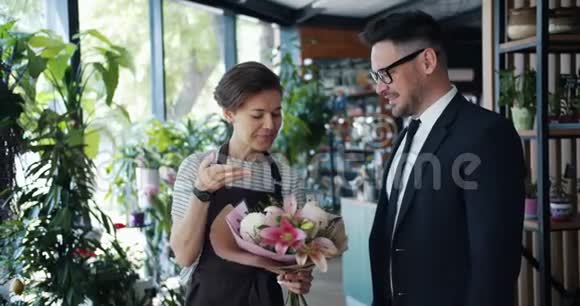 女花店老板和店里拿着一束花的男顾客交谈视频的预览图
