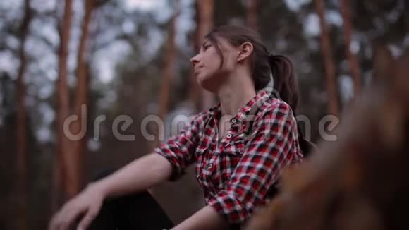 女人坐在森林的树干上放松地环顾四周视频的预览图