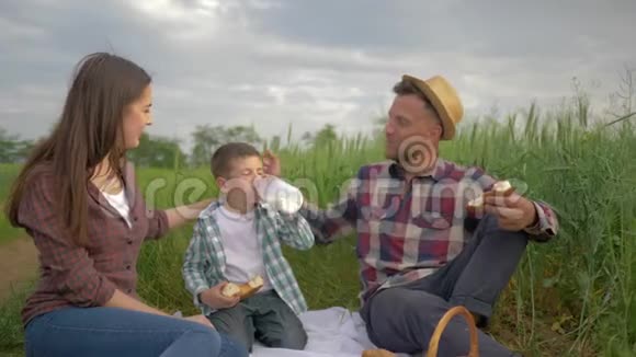 年轻的妈妈和爸爸小儿子一起吃苹果和羊角面包一边喝牛奶一边放松交流视频的预览图