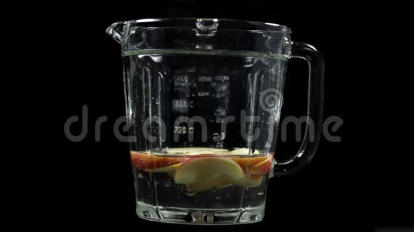 苹果落在搅拌机里有水混合制成家庭果汁慢运动黑色背景视频的预览图