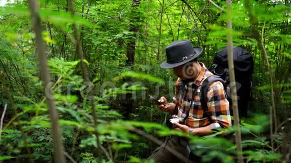 带背包的男士旅行者用智能手机在天然森林里自拍视频的预览图