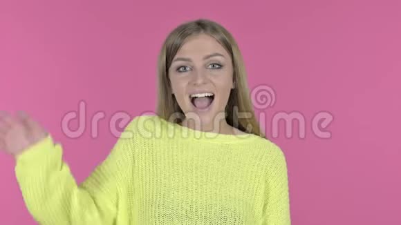 迷人的少女在镜头前挥手粉色背景视频的预览图