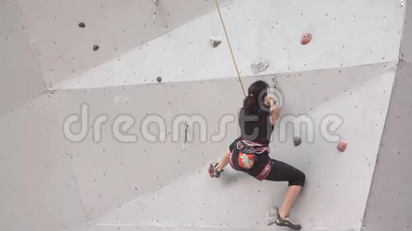 年轻女子在室内攀岩墙上锻炼慢动作在攀岩墙上训练登山者女孩视频的预览图