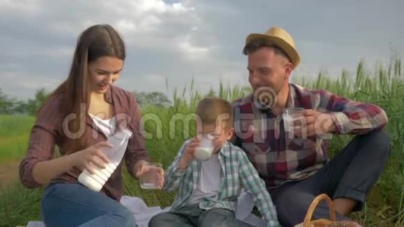 家庭野餐快乐的年轻夫妇和小男孩一起喝牛奶同时在野外放松视频的预览图