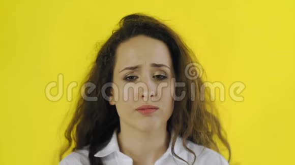 悲伤体贴年轻漂亮的女人穿着衬衫站在黄色背景的工作室里视频的预览图