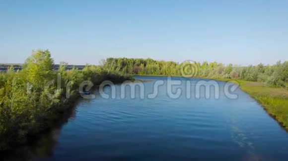 夏季阳光明媚的天气宁静的小河和岸边的树木的鸟瞰图摄像机沿着海岸飞行视频的预览图