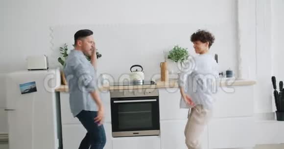 穿休闲服装的欢乐男女在公寓的厨房里欢笑视频的预览图