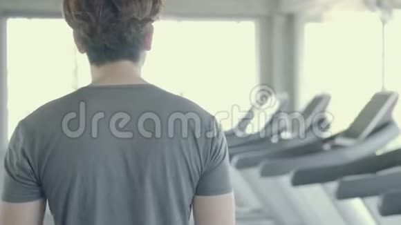 英俊的亚洲年轻人在健身房步行到跑步机亚洲男人锻炼做有氧运动以促进健康视频的预览图