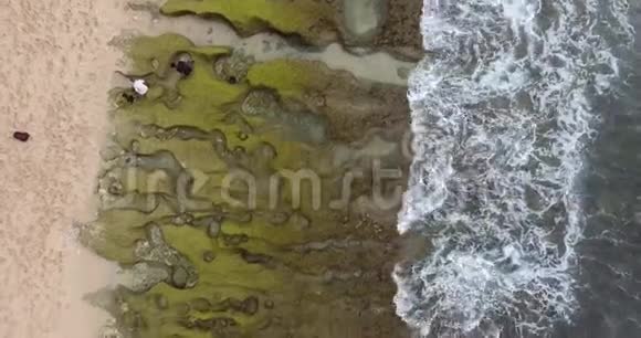 巴厘岛岩石海岸的俯视图沙滩和岩石海浪4k视频的预览图