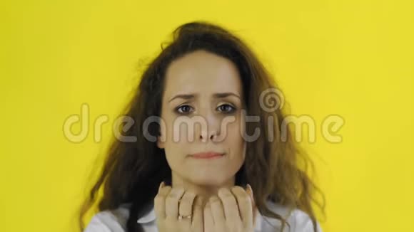 悲伤体贴年轻漂亮的女人穿着衬衫站在黄色背景的工作室里视频的预览图