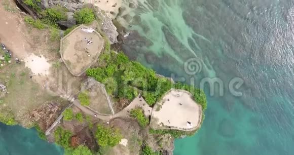 巴厘岛岩石海滩上的俯视图有巨大的悬崖和步行者4k视频的预览图