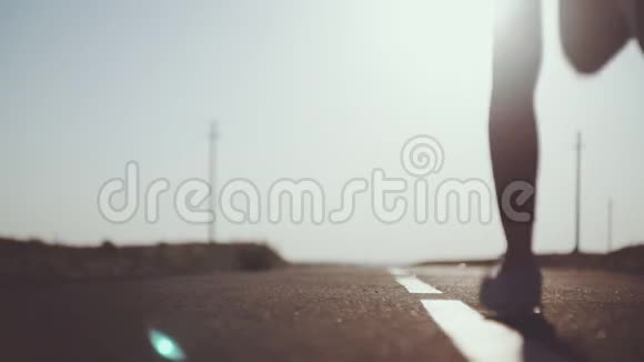 日落时分阳光明媚的柏油路上有一个年轻的运动女孩视频的预览图