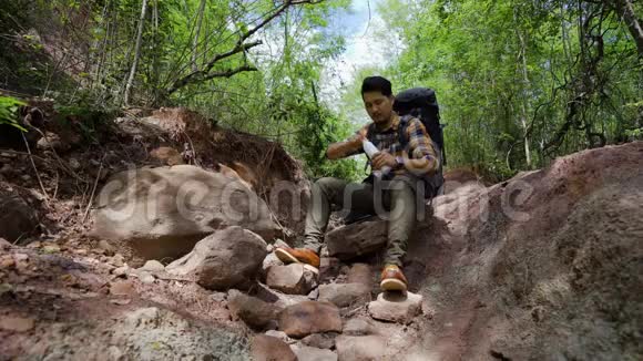 疲惫的旅行者背着背包在天然森林里休息和污染水视频的预览图