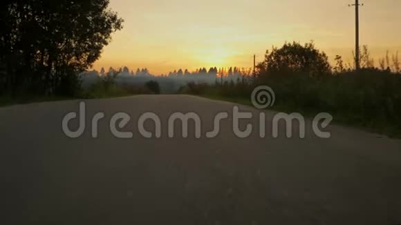在日落的背景下摄像机沿着郊区的柏油路移动视频的预览图
