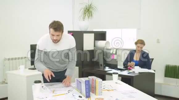女人在电脑上工作男人在办公室里找房子的图纸视频的预览图